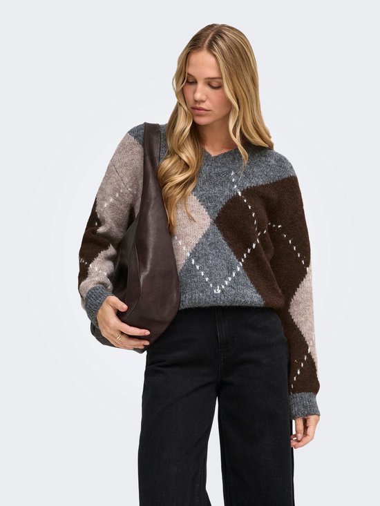 Model kijkt naar beneden, draagt een v-hals trui met argyle-patroon in grijstinten, bruin en beige met een donkere schoudertas.
