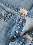 Detail van de knoopsluiting en label met 'Jack & Jones Jeans Intelligence' op een blauwe jeans.