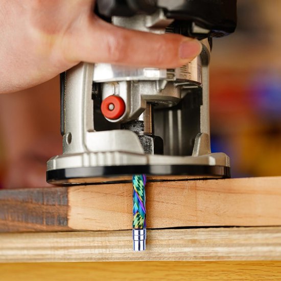Hand die een bovenfreesmachine vasthoudt met een regenboogkleurige frees in een houten werkstuk.