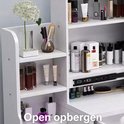 Witte kaptafel met open opbergplanken en diverse cosmetica-artikelen.