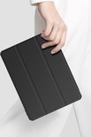 Vrouw in wit shirt die een zwarte tablet hoes vasthoudt.