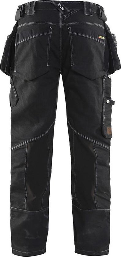 Achterkant van zwarte werkjeans met vele zakken, riemlussen en witte stiksels.