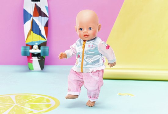 BABY born pop in lichtblauw jasje met roze mouwen en roze broek. Jasje met print en gele rits. Achter de pop een kleurrijk skateboard.