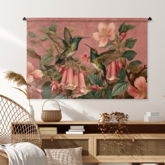 Wandkleed met roze achtergrond, twee kolibries tussen bloemen, boven een dressoir.