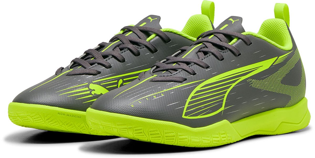 Grijze Puma Ultra 5 Play It Low voetbalschoenen met groene accenten, lichtgewicht bovenwerk en lage rubberen buitenzool.