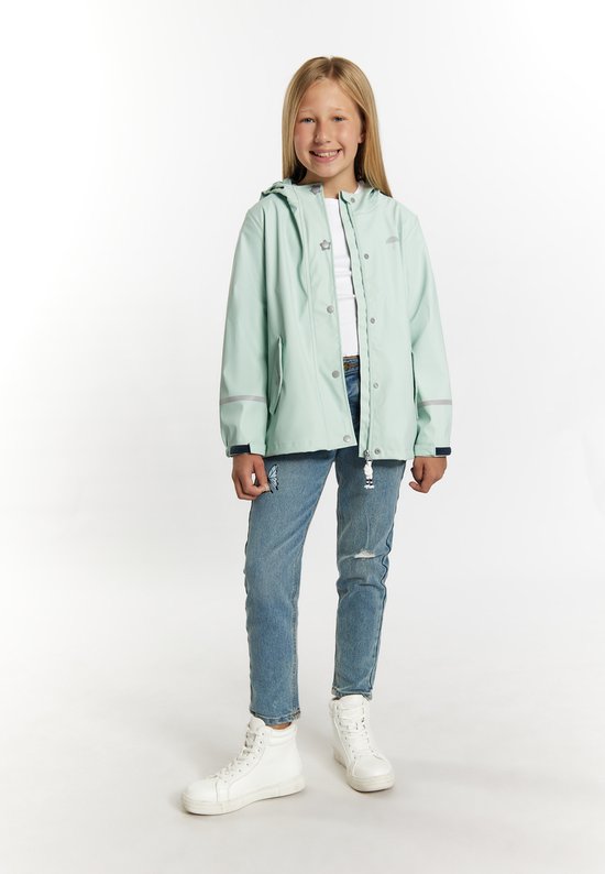 Jong meisje met blond haar, draagt een lichtgroene regenjas, spijkerbroek met scheuren en witte sneakers.