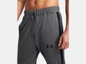 Detail van de broek van een grijs Under Armour trainingspak. Elastische tailleband met trekkoord, zwarte streep en logo.