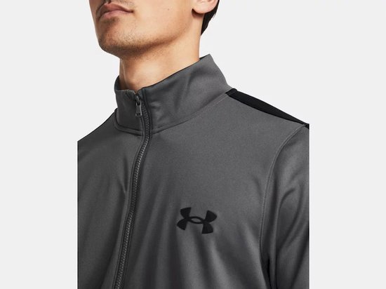 Grijs trainingsjack met zwarte strepen op de mouwen en een zwart Under Armour logo.