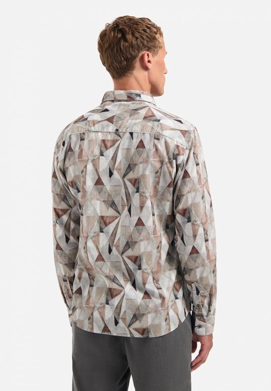 Model draagt een overhemd met all-over geometrische print in bruin-, grijs- en wittinten op corduroy.