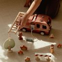 Kind speelt met houten brandweerwagen, ladder, poppetjes, boom, hydrant en vuurelementen.