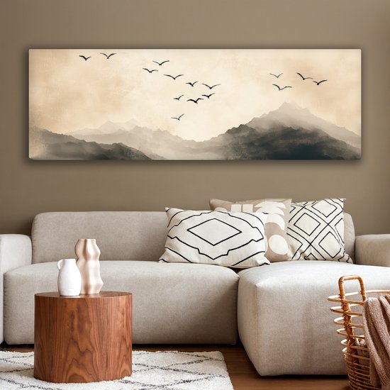 Une toile panoramique représentant un paysage de montagnes et d'oiseaux en vol, dans des tons sépia, au-dessus d'un canapé.