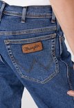 Close-up van de achterzak van een spijkerbroek met het 'Wrangler'-logo op een bruin label.
