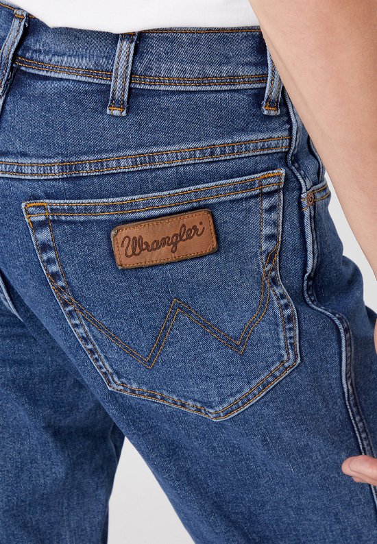 Close-up van de achterzak van een spijkerbroek met het 'Wrangler'-logo op een bruin label.