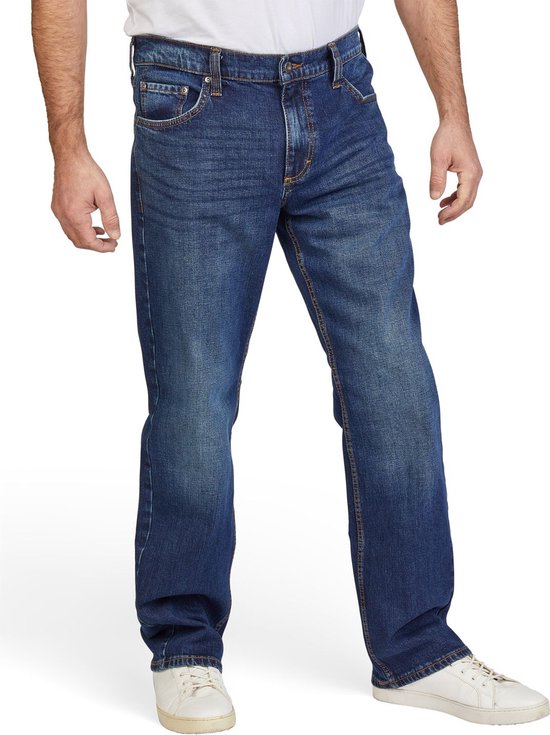 Man in blauwe jeans met rechte pijpen, licht vervaagd effect en witte sneakers.