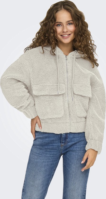 Model lachend in crèmekleurige teddy jas met rits, capuchon, klepzakken en spijkerbroek.