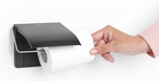 Porte-rouleau toilette noir avec rabat, une main remplace le rouleau.