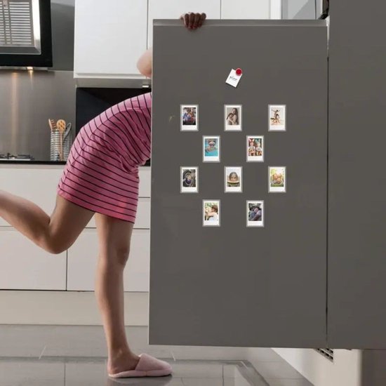Een vrouw in een gestreepte jurk kijkt naar tien magnetische fotolijstjes op een koelkast.