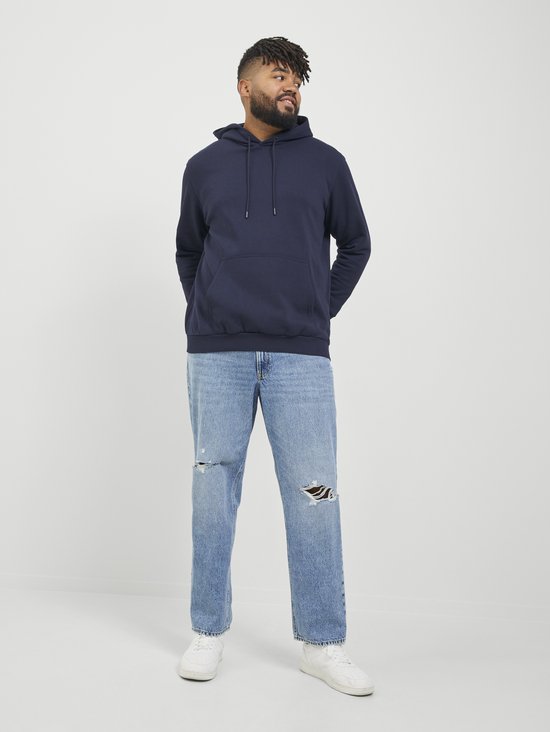 Man in een donkerblauwe hoodie met capuchon en jeans met scheuren.