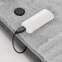 Grijze, zachte deken met aan/uit knop en aangesloten powerbank.