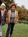 Jongens in een bruine parka met imitatiebont voering en een donkergroene hoodie.