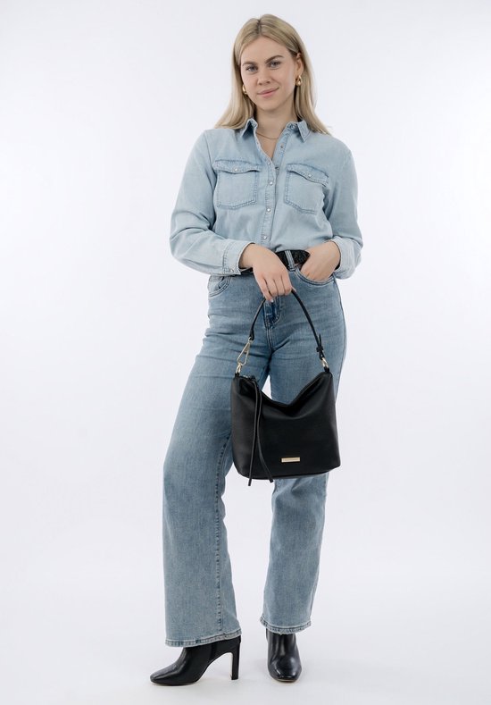 Model draagt een zwarte schoudertas, gecombineerd met een spijkerblouse en jeans.