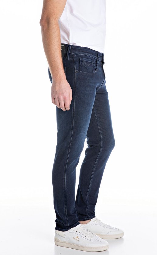 Man in een donkerblauwe spijkerbroek, gezien vanaf de zijkant.
