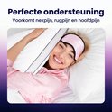 Vrolijke vrouw met slaapmasker omarmt Soulsnooze kussen in bed.