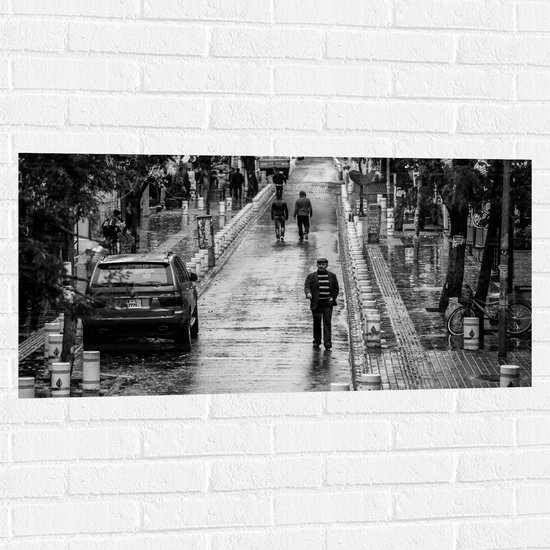 WallClassics - Muursticker - Man wandeldn door Dorpje (zwart/wit) - 100x50 cm Foto op Muursticker