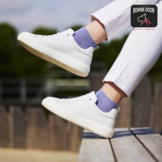 Blauwe sokken in witte sneakers, gedragen door een vrouw.