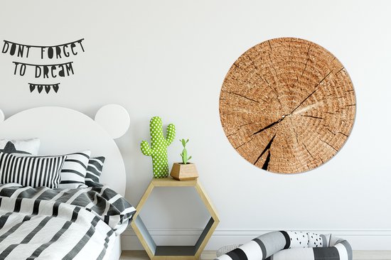 Décoration murale ronde en bois avec cernes annuels au-dessus d'un lit.