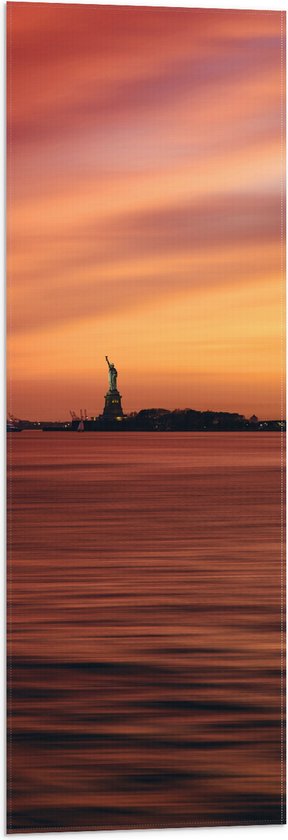 WallClassics - Vlag - Oranje Lucht boven Vrijheidsbeeld in New York - 30x90 cm Foto op Polyester Vlag