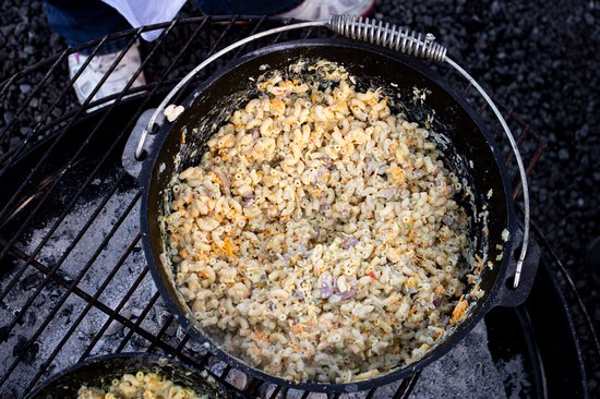 Gietijzeren pan met macaroni en kaas, rokend boven kolen.