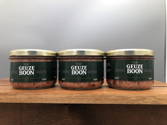 Drie glazen potten Oude Geuze Boon paté naast elkaar op een houten plank. Elke pot heeft een donkergroen etiket met witte tekst.
