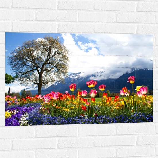 WallClassics - Muursticker - Felgekleurde Bloemen in het Veld met Berg en Boom - 90x60 cm Foto op Muursticker