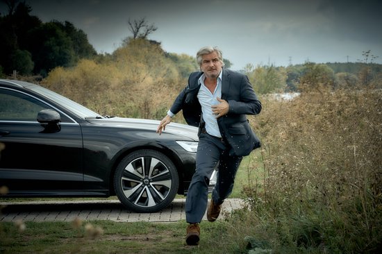 Man in pak rent weg van een zwarte auto, weg van het pad.