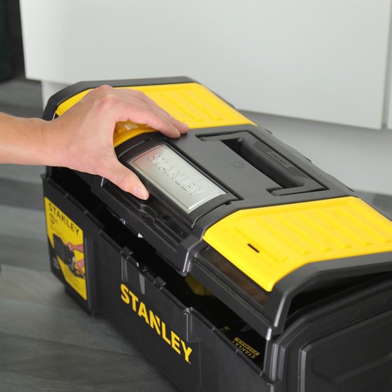 Hand opent de gesloten Stanley gereedschapskoffer met gele deksels.