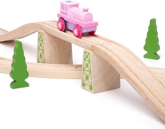 Roze en paarse speelgoedtrein op een houten brug met groene bomen.