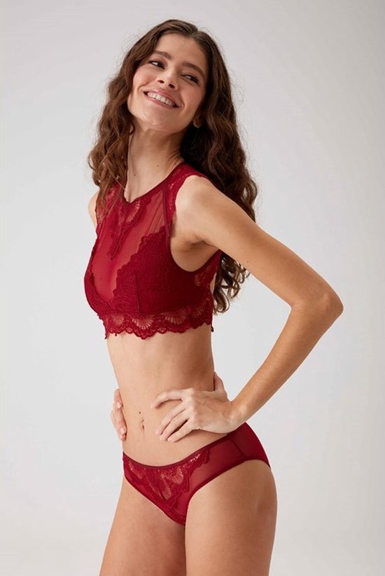 Vrouw van voren lachend in een bordeauxrode kanten crop top met ingebouwde cups en bijpassende slip, handen op de heupen.