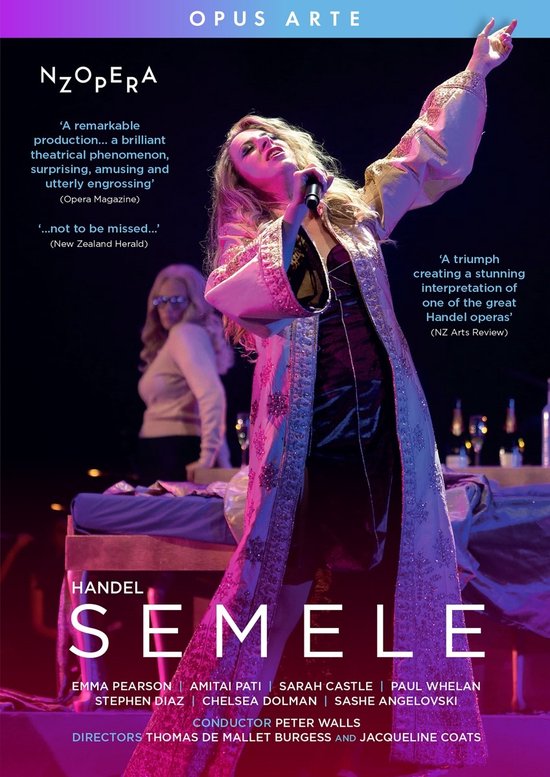 Een vrouw in een lange, met juwelen versierde, geborduurde badjas, zingend met een microfoon. NZOPERA HANDEL SEMELE.