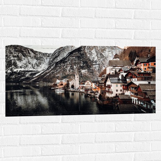WallClassics - Muursticker - Klein Dorpje tussen Bergen bij Water - 100x50 cm Foto op Muursticker