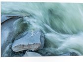 WallClassics - PVC Schuimplaat- Blauw Stromend Water langs Stenen - 75x50 cm Foto op PVC Schuimplaat