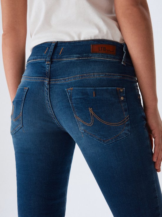 Achterkant van een blauwe jeans met LTB-logo en oranje stiksels, gedragen met een witte top.