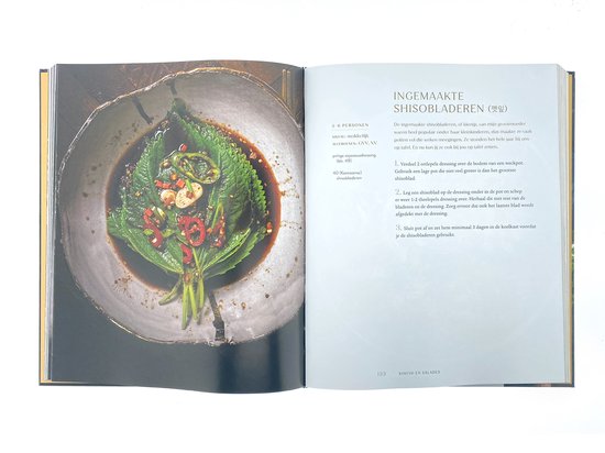 Een open kookboek met een recept voor ingemaakte shiso bladeren, met chilipepers en knoflook.