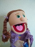 Poppenkastpop Amy met bruine vlechten, groen-witte ogen en paars shirt.