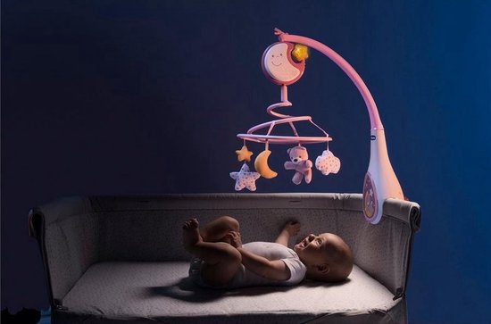 Baby in een co-sleeper kijkt omhoog naar een roze muziekmobiel met een lachende maan.