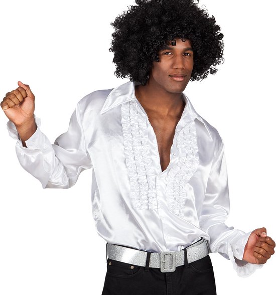 Man met afro-pruik, draagt een glanzend wit overhemd met ruches, een zilveren riem en zwarte broek.