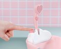 Vinger drukt op de roze knop van de douchekop met hartvormige, oplichtende lamp.