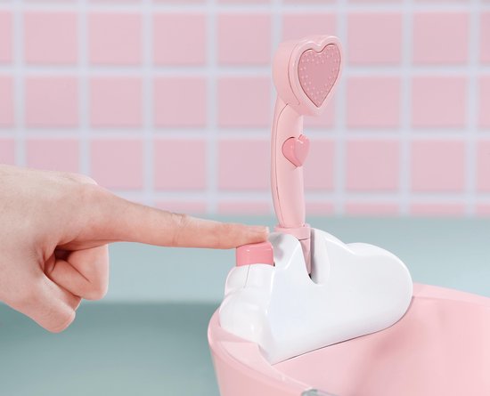 Vinger drukt op de roze knop van de douchekop met hartvormige, oplichtende lamp.