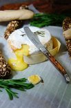 Smeltende camembert met een Laguiole botermes met olijfhouten handvat.