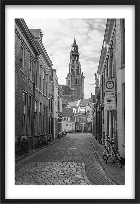 Photo en noir et blanc d'une rue de Groningen avec une tour d'église et un panneau de signalisation, cadre noir.